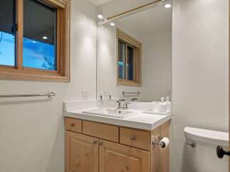 This bathroom features a clean and modern vanity with ample storage space, complemented by a large mirror reflecting the natural light from the window.