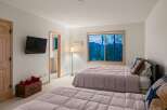 Experience serene mountain living in this charming bedroom featuring two comfortable beds and a large window with breathtaking views of the surrounding landscape.