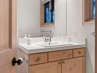 This bathroom features a light wood vanity with ample storage, topped with a clean white countertop.