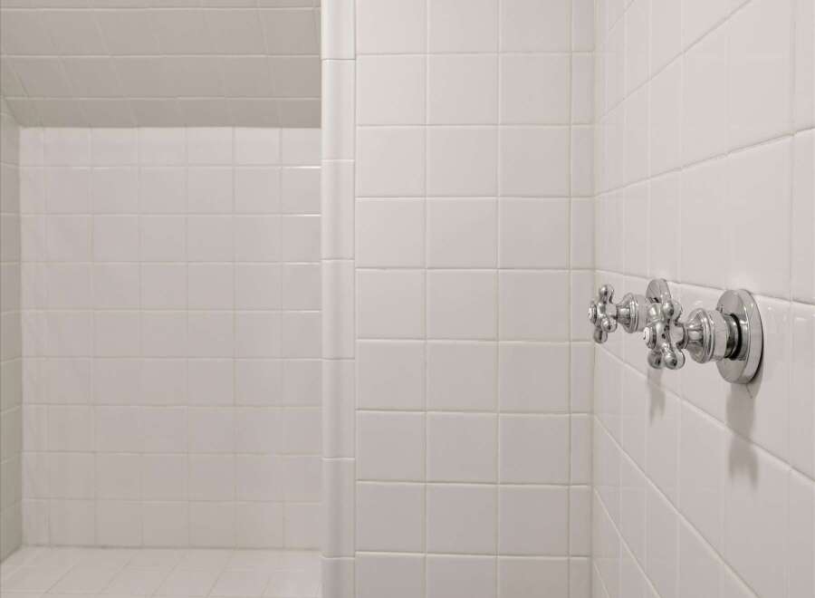 Step into this pristine white tiled shower, featuring a built-in bench for ultimate comfort and relaxation.