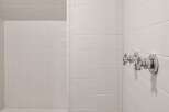 Step into this pristine white tiled shower, featuring a built-in bench for ultimate comfort and relaxation.