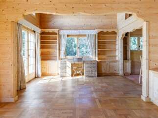 Discover this charming wooden interior featuring built-in bookshelves and a desk area, perfect for a home office or study.