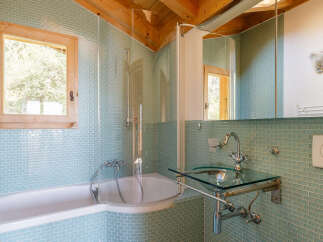 This charming bathroom features a relaxing bathtub and a modern glass-top vanity with a chrome faucet.