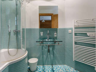 Experience modern comfort in this beautifully appointed bathroom, featuring a sleek glass vessel sink and a spacious bathtub with a glass shower enclosure.