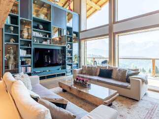 Experience luxury mountain living in this stunning living room, featuring a floor-to-ceiling custom bookshelf and expansive windows with breathtaking panoramic views.