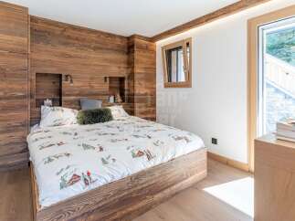 Experience rustic charm in this cozy bedroom featuring a wooden accent wall and a comfortable bed with playful ski-themed bedding.