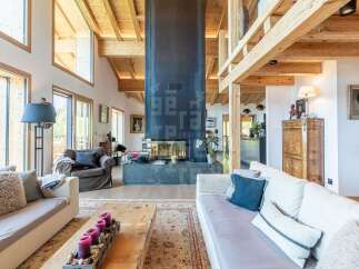 Experience luxury mountain living in this stunning chalet featuring a grand fireplace and exposed wooden beams.
