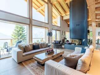 Experience luxury mountain living in this stunning chalet, boasting expansive floor-to-ceiling windows that frame breathtaking panoramic views of snow-capped peaks and lush forests.