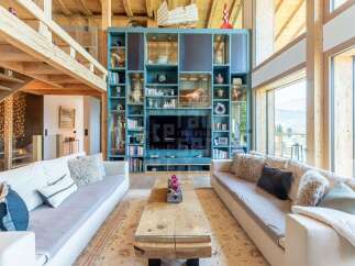 Experience luxury living in this stunning mountain retreat, featuring a spacious open-plan living area with comfortable seating and a large wooden coffee table.