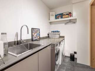 Discover this modern laundry room featuring a deep stainless steel sink and a sleek countertop, perfect for all your washing needs.