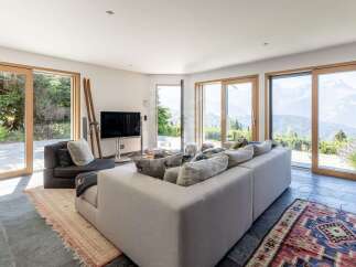 Experience breathtaking mountain views from this modern living room, featuring expansive floor-to-ceiling windows and sliding glass doors that seamlessly connect indoor and outdoor spaces.