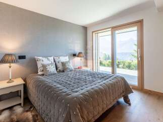 Experience serene mountain living in this exquisite bedroom, featuring a plush quilted bed adorned with decorative pillows and a cozy bedside lamp.