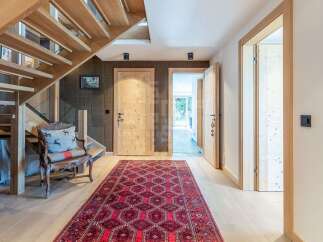 Experience rustic charm in this inviting entryway, featuring a warm wooden staircase and a traditional Persian rug.