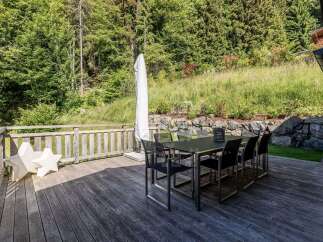 Enjoy al fresco dining on this spacious wooden deck, perfect for entertaining guests amidst a lush, natural backdrop.
