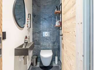 Discover this modern bathroom featuring a sleek stone sink and a wall-mounted toilet with a dual-flush system.