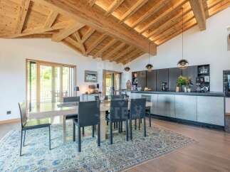 Experience luxurious alpine living in this stunning dining and kitchen area, featuring a grand wooden beamed ceiling and expansive windows that flood the space with natural light.