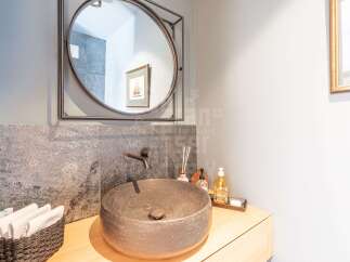 This modern bathroom features a striking stone vessel sink paired with a sleek wall-mounted faucet.