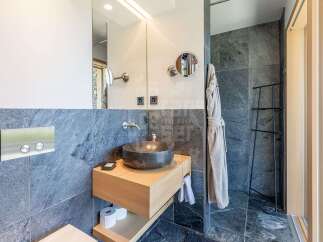 Experience modern luxury in this stunning bathroom, featuring a sleek stone vessel sink atop a floating wood vanity.