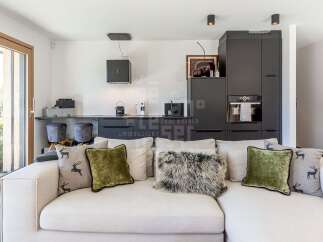 Experience modern living in this stylish apartment, featuring a sleek, integrated kitchen with dark cabinetry and high-end appliances.