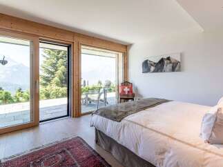 Experience breathtaking mountain views from this serene bedroom, featuring expansive sliding glass doors that open to a private balcony.