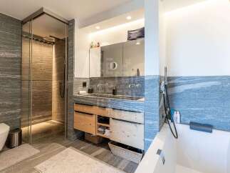 Experience modern luxury in this stunning bathroom featuring a spacious walk-in shower with elegant stone tile and a rainfall showerhead.