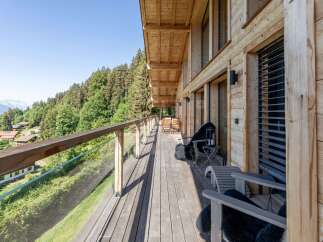 Experience breathtaking mountain views from this stunning wooden chalet's expansive balcony.