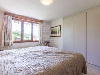 This charming bedroom features a large window with striped curtains, offering a glimpse of the lush greenery outside.