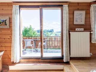 Enjoy breathtaking mountain views from this charming wooden cabin, featuring a spacious balcony with outdoor seating perfect for morning coffee or evening relaxation.