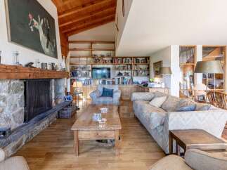 Experience rustic charm in this spacious living room, featuring a grand stone fireplace and a vaulted wooden ceiling.