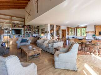 This spacious open-plan living area features a cozy fireplace, extensive built-in bookshelves, and a large television, perfect for relaxation and entertainment.