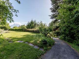 Escape to this serene mountain retreat, featuring a lush green lawn perfect for relaxation and a winding pathway leading to breathtaking panoramic views.