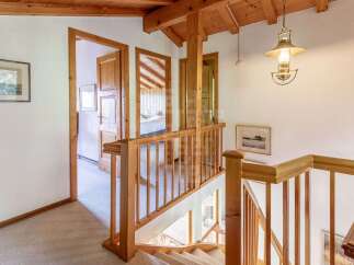 Ascend to the upper level of this charming home via a beautifully crafted wooden staircase, featuring a sturdy banister and elegant spindles.