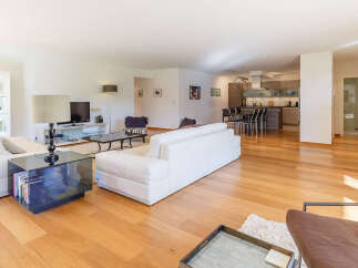 Experience modern living in this spacious open-concept apartment, featuring a sleek white sectional sofa and a stylish glass coffee table.