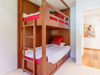 This charming bedroom features a space-saving wooden bunk bed with built-in drawers, perfect for maximizing room utility.