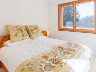 Experience comfort and style in this inviting bedroom, featuring a plush bed adorned with decorative pillows and a beautiful floral runner.