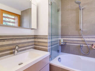 This modern bathroom features a sleek white sink with a chrome faucet, complemented by a striped tile backsplash.