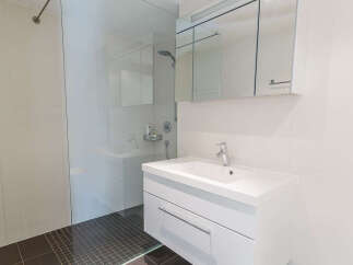 Experience modern comfort in this beautifully appointed bathroom, featuring a sleek vanity with ample storage and a pristine white countertop.