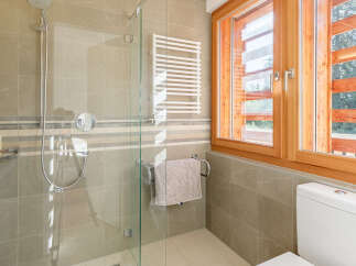 Experience modern comfort in this beautifully appointed bathroom, featuring a spacious glass-enclosed shower with a rainfall showerhead and a convenient towel warmer.