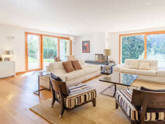 Experience luxurious living in this spacious, modern living room featuring comfortable white leather sofas and a sleek fireplace.