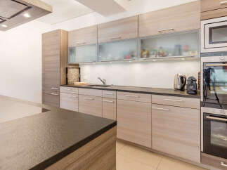 Experience modern living in this stunning kitchen featuring sleek, light wood cabinetry and frosted glass upper cabinets.
