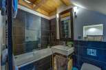 This modern bathroom features a sleek bathtub with a glass enclosure, complemented by dark tiled walls and a wooden ceiling.