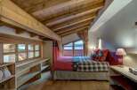 Experience cozy mountain living in this charming bedroom featuring a rustic wooden ceiling with exposed beams and a comfortable bed adorned with plaid bedding.