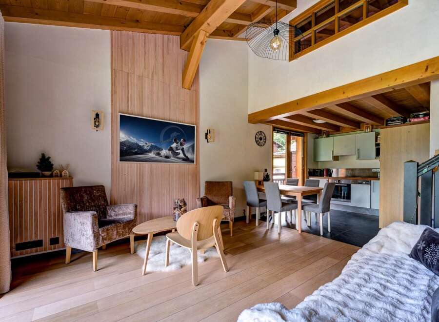 Experience the charm of this mountain retreat, featuring a spacious living area with a vaulted wooden ceiling and exposed beams.