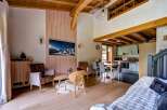 Experience the charm of this mountain retreat, featuring a spacious living area with a vaulted wooden ceiling and exposed beams.