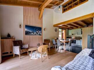 Experience the charm of this mountain retreat, featuring a spacious living area with a vaulted wooden ceiling and exposed beams.