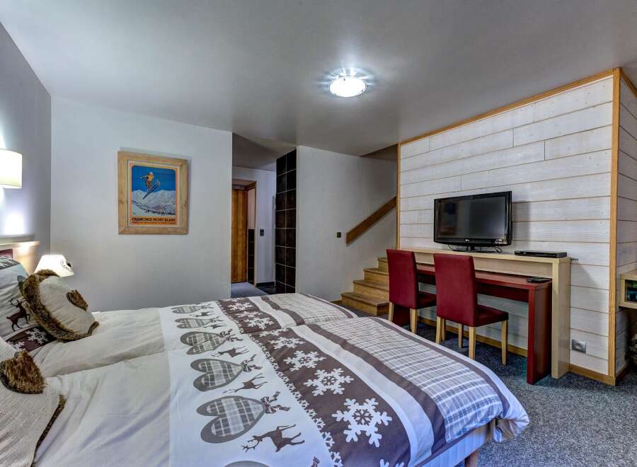 This charming bedroom features two comfortable beds adorned with festive deer and snowflake-themed linens, perfect for a cozy mountain getaway.