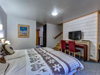 This charming bedroom features two comfortable beds adorned with festive deer and snowflake-themed linens, perfect for a cozy mountain getaway.