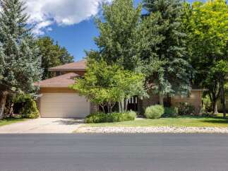 Discover this charming home featuring a spacious two-car garage and a welcoming front entrance surrounded by mature trees and lush landscaping.