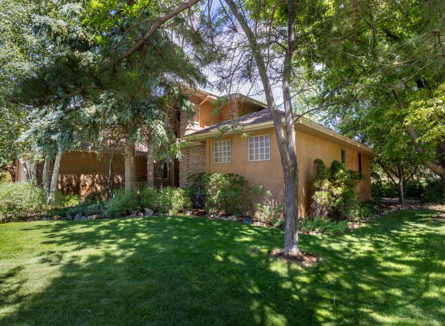 Nestled amidst lush greenery, this charming home offers a serene retreat with its stucco exterior and inviting facade.