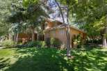 Nestled amidst lush greenery, this charming home offers a serene retreat with its stucco exterior and inviting facade.